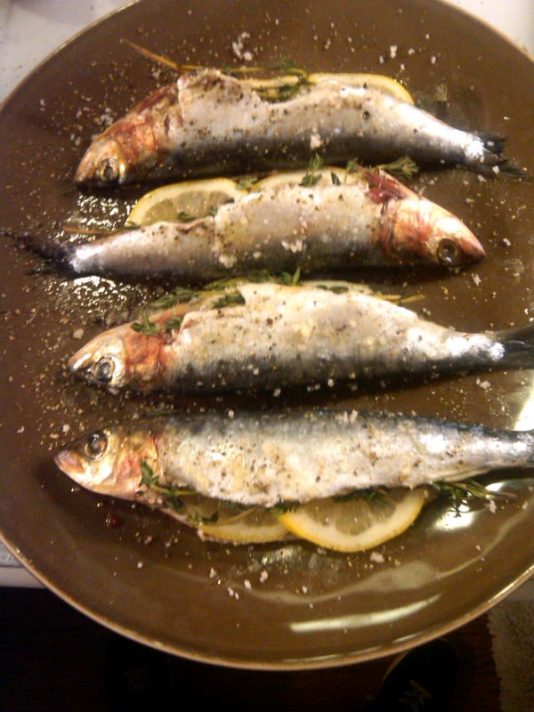 Grilled sardines on a brown plate.
