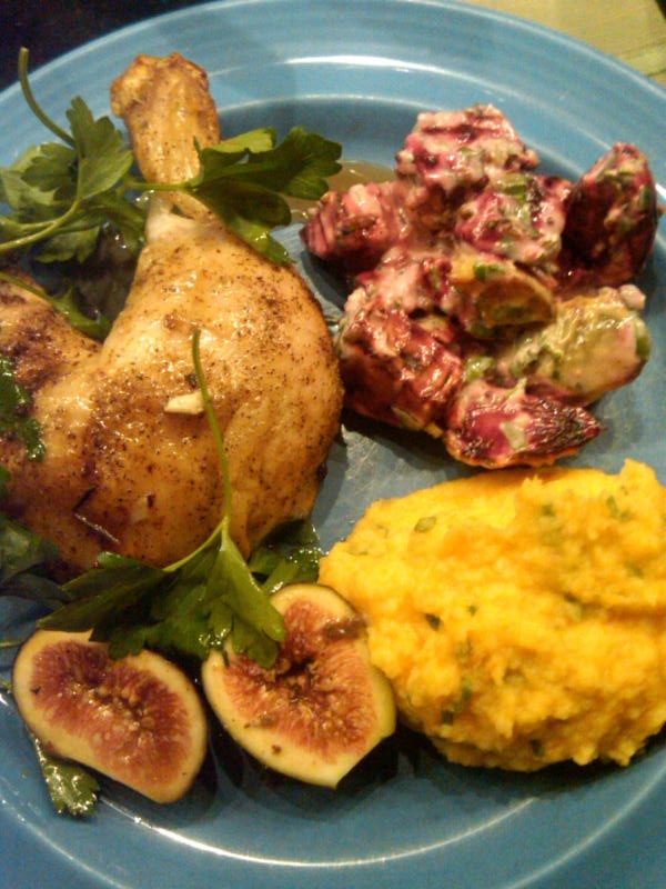 Carrot and parsnips with beets and roasted chicken leg on a blue plate.