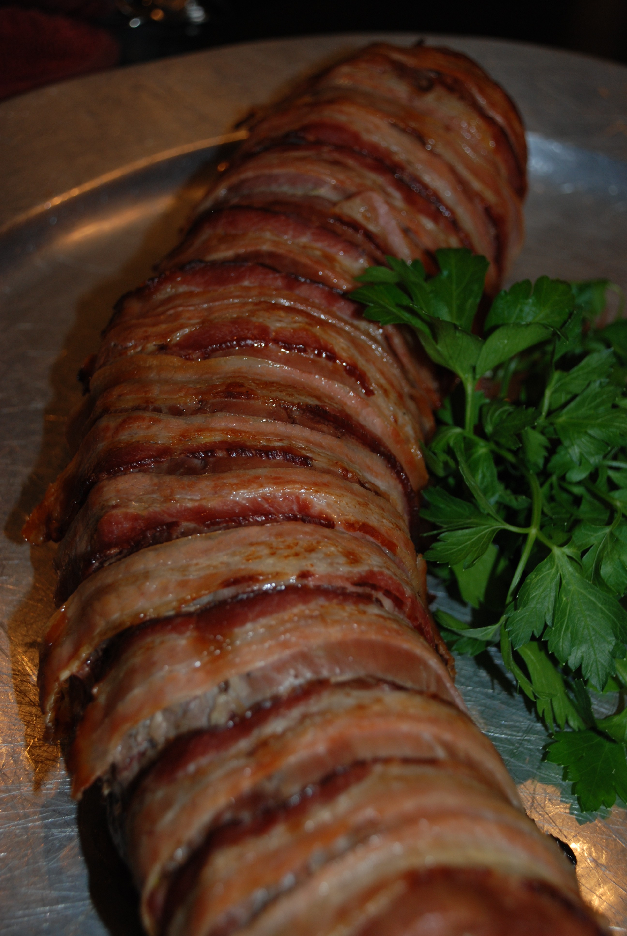 Bacon wrapped beef tenderloin on a metal platter.