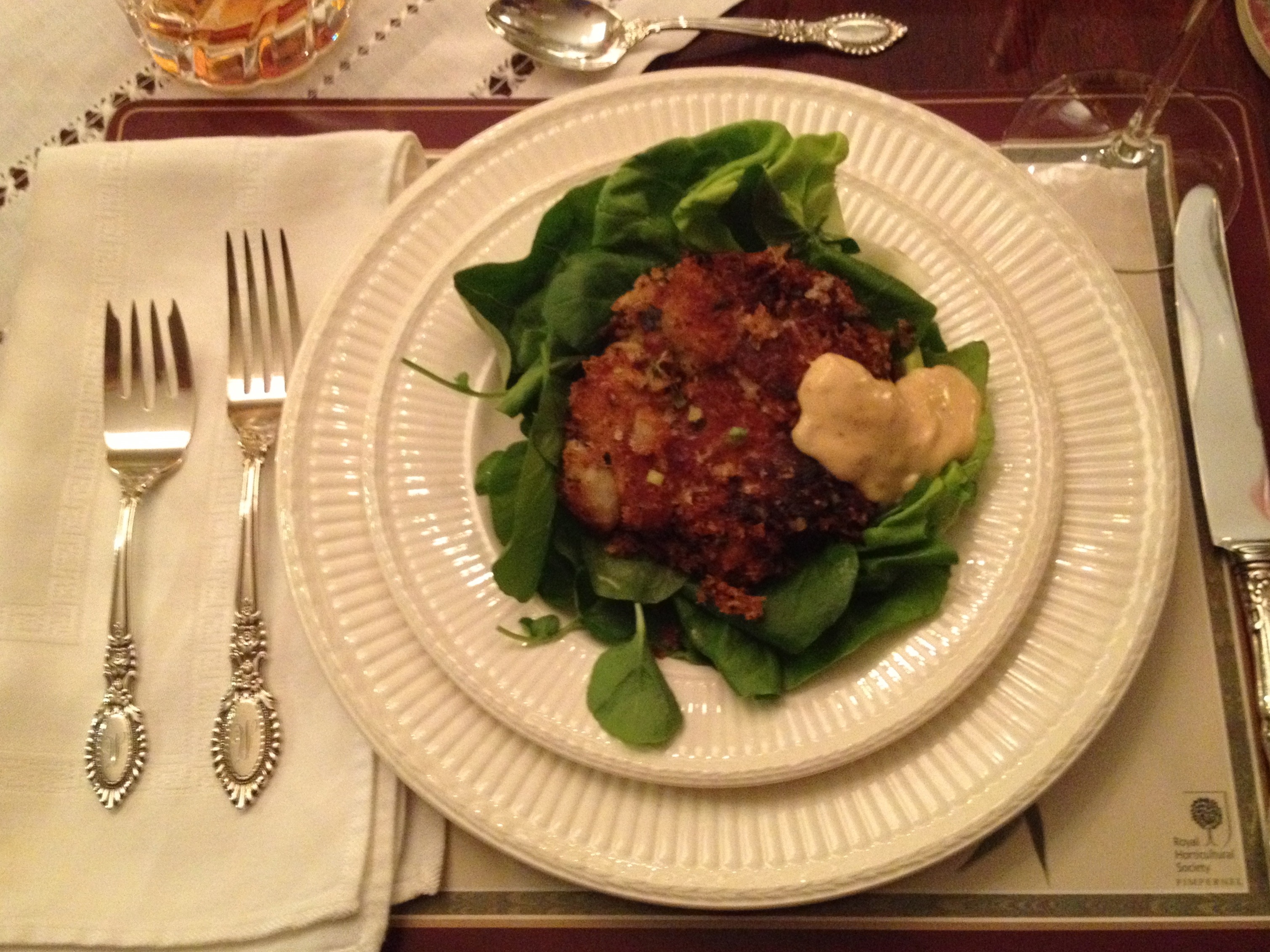 Crab cakes and lettuce on white dinner plates.