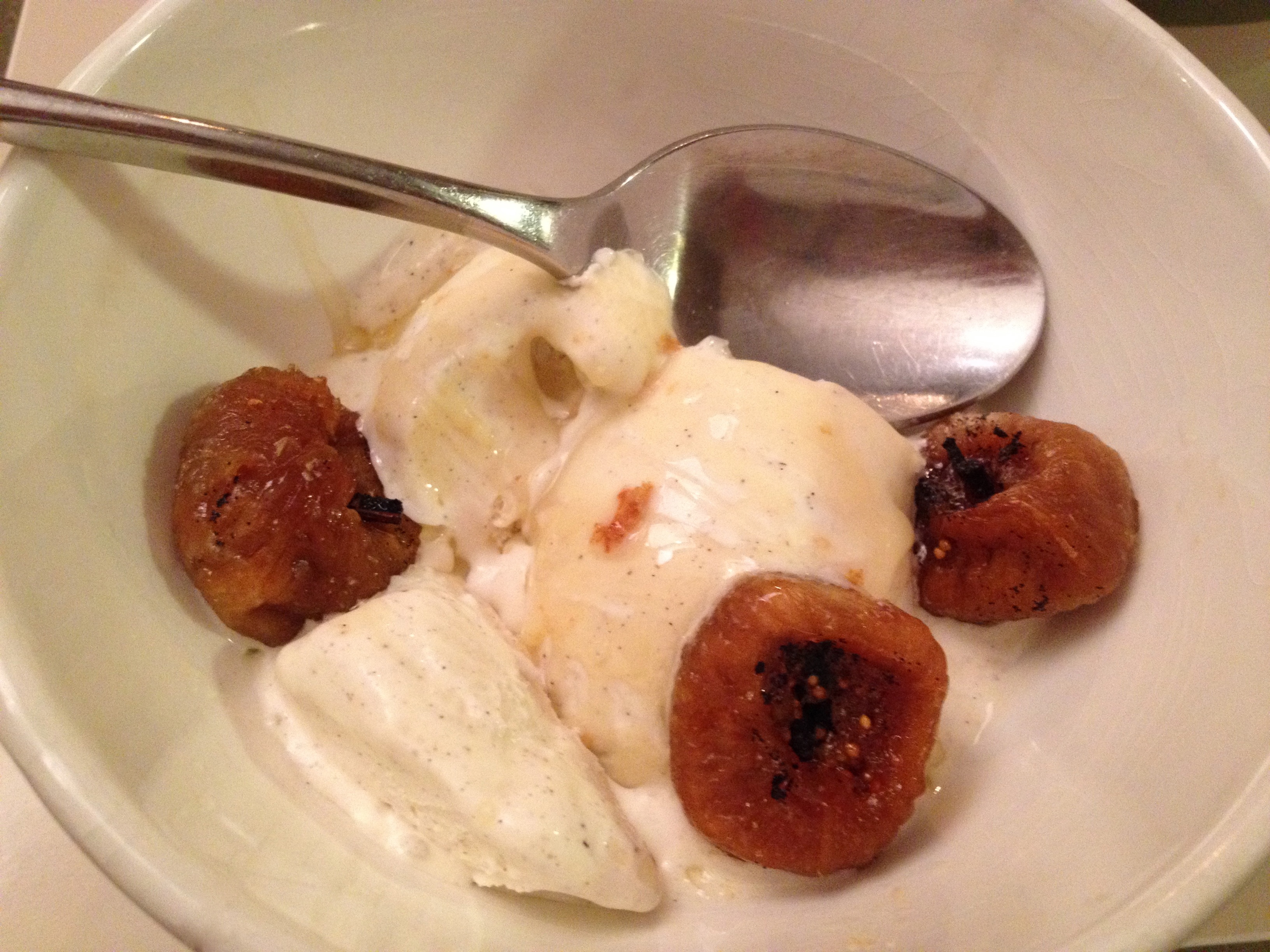 Ice cream and sauteed figs in a white bowl.
