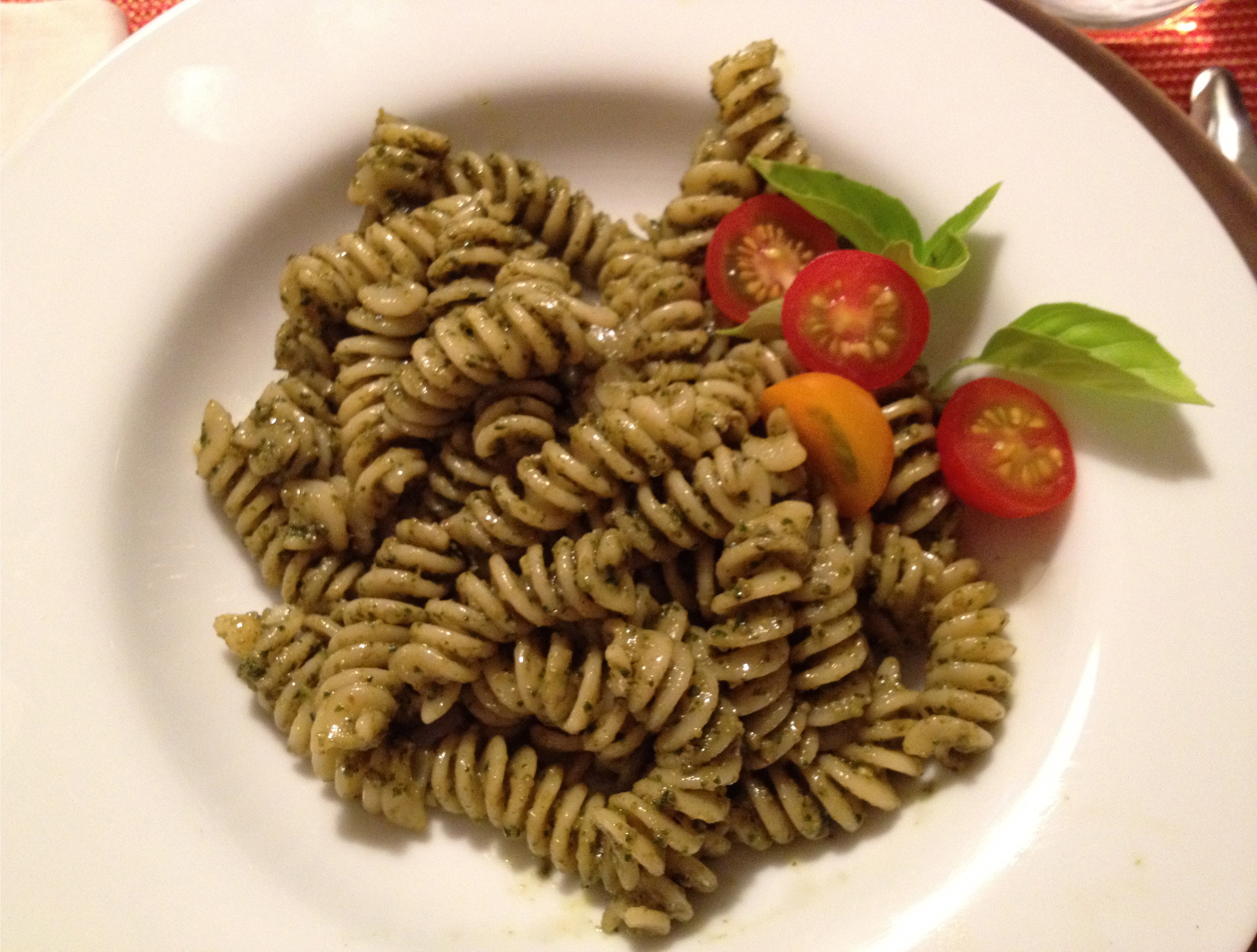 Pesto pasta and tomatoes in a white bowl.