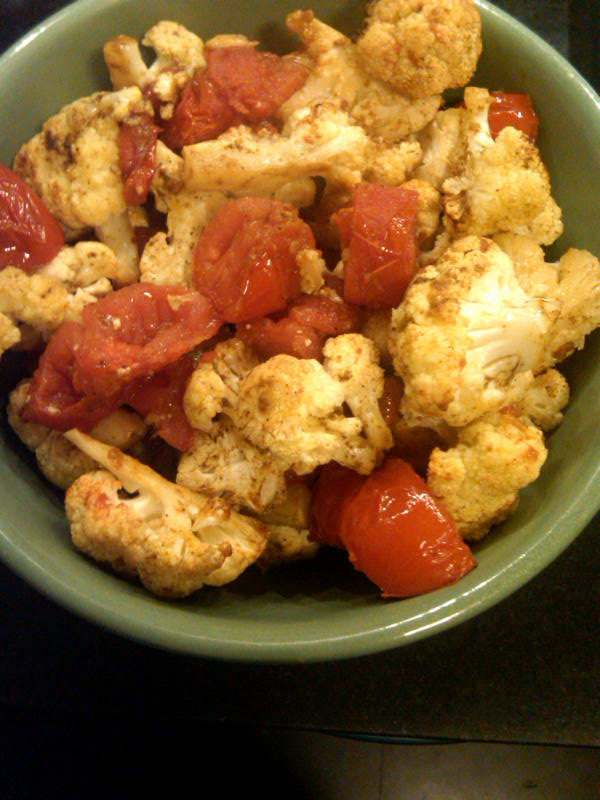 Roasted cauliflower with cumin and tomatoes in a green bowl.