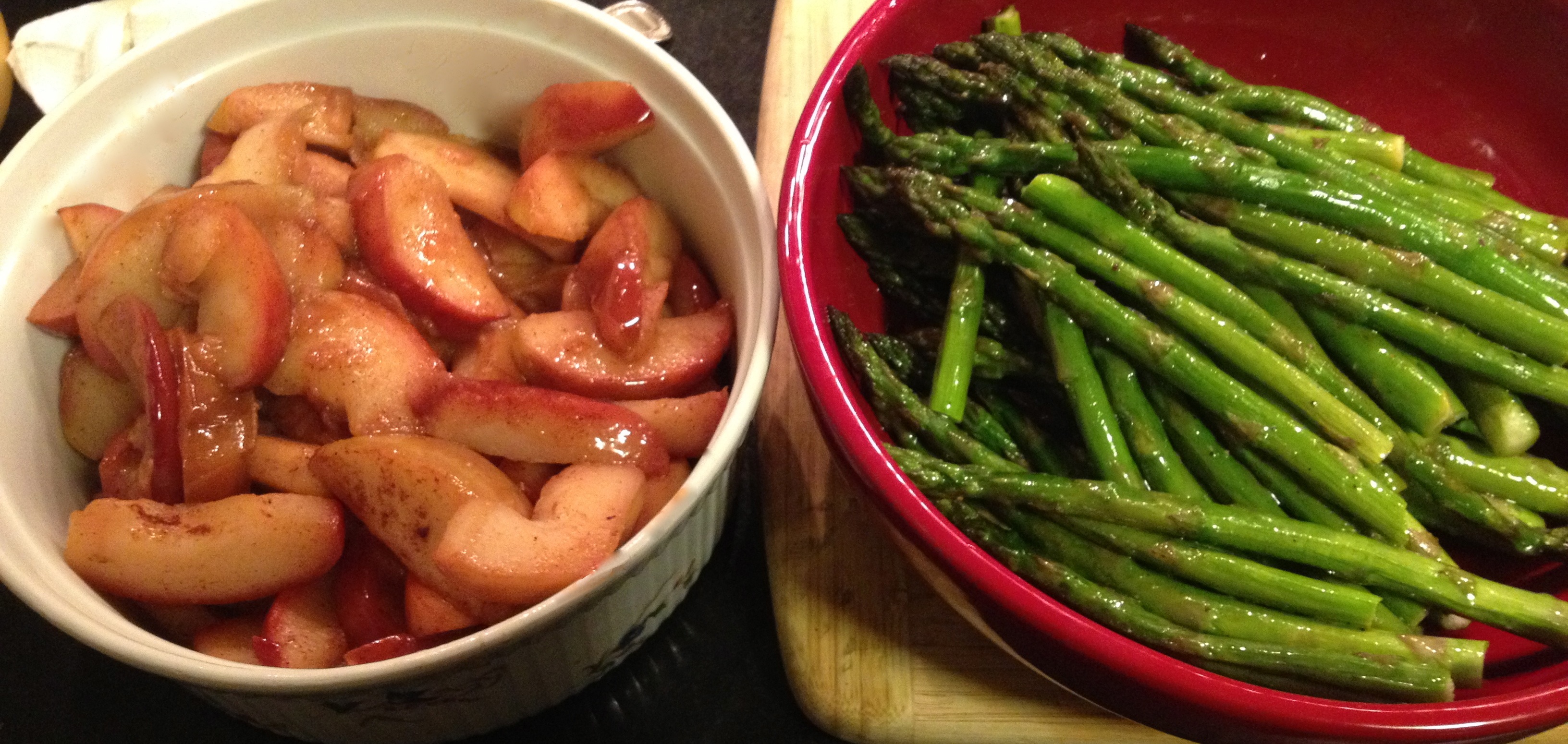 Sauteed apples in butter with cinnamon, nutmeg and lemon; roasted asparagus with olive oil and lemon in a red holiday bowl.