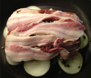 Raw bacon covering an herb marinated pork loin roast.