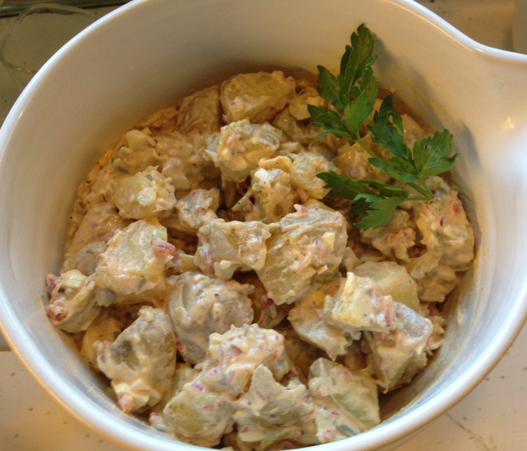Midwest potato salad in a white Le Crueset bowl garnished with parsley.