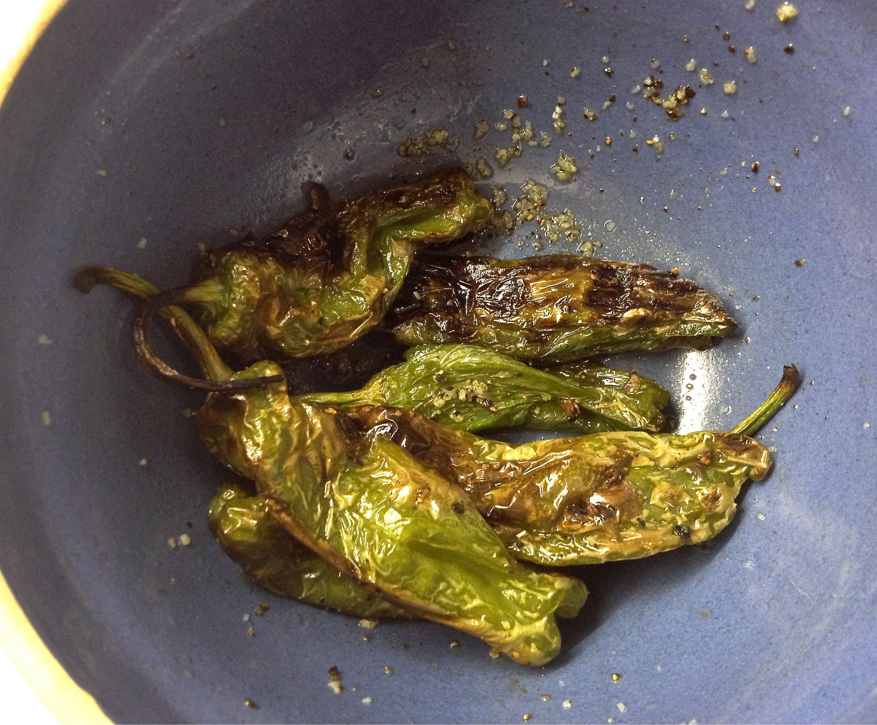 Grilled shisido peppers in an antique blue pottery bowl.