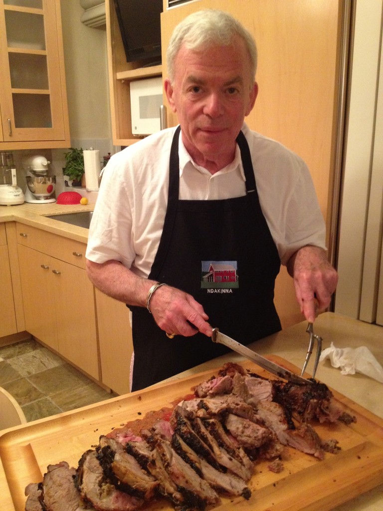 Carving Herb and Honey Mustard Crusted Leg of Lamb on a wooden cutting board in a NYC apartment.