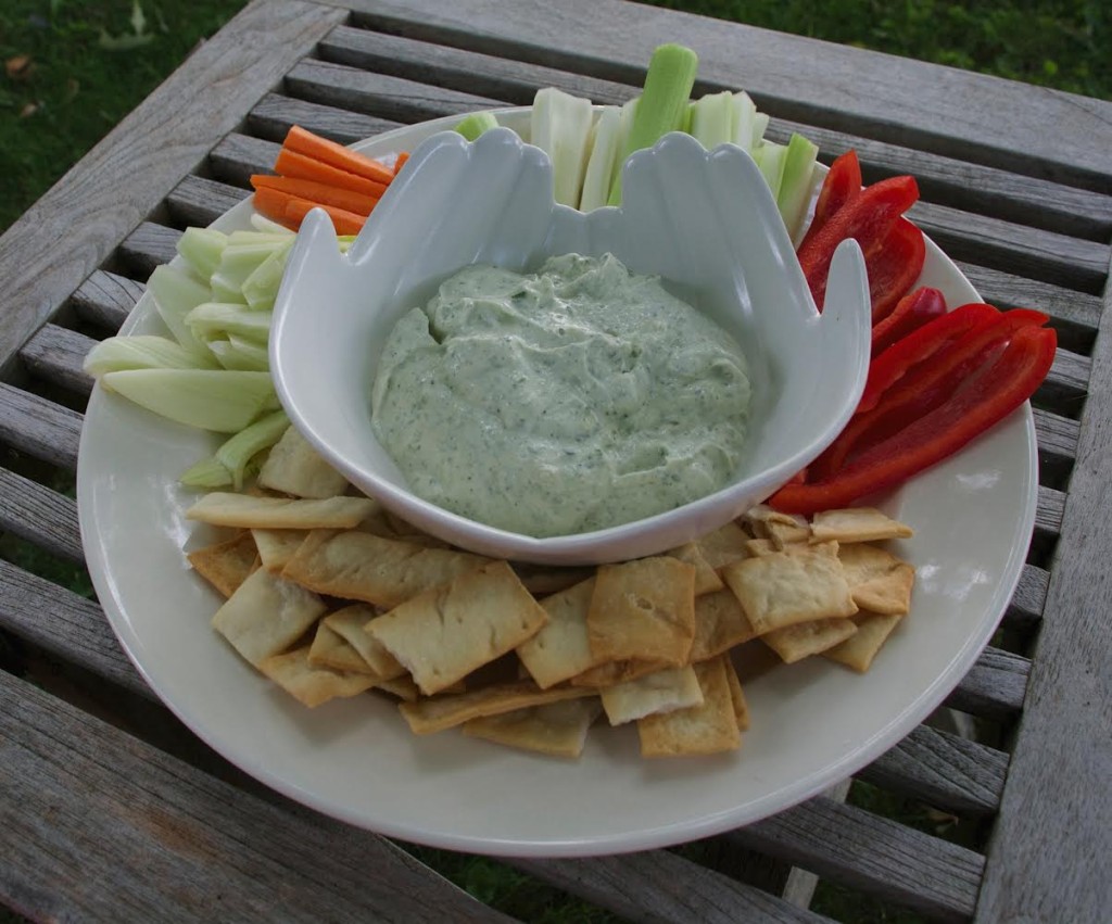 Spinach mix dip in a bowl with crudites and crackers.