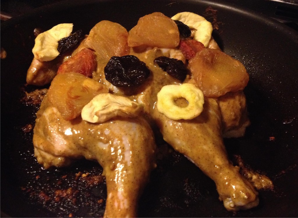 Mustard and cumin coated whole chicken with dried fruit on top.
