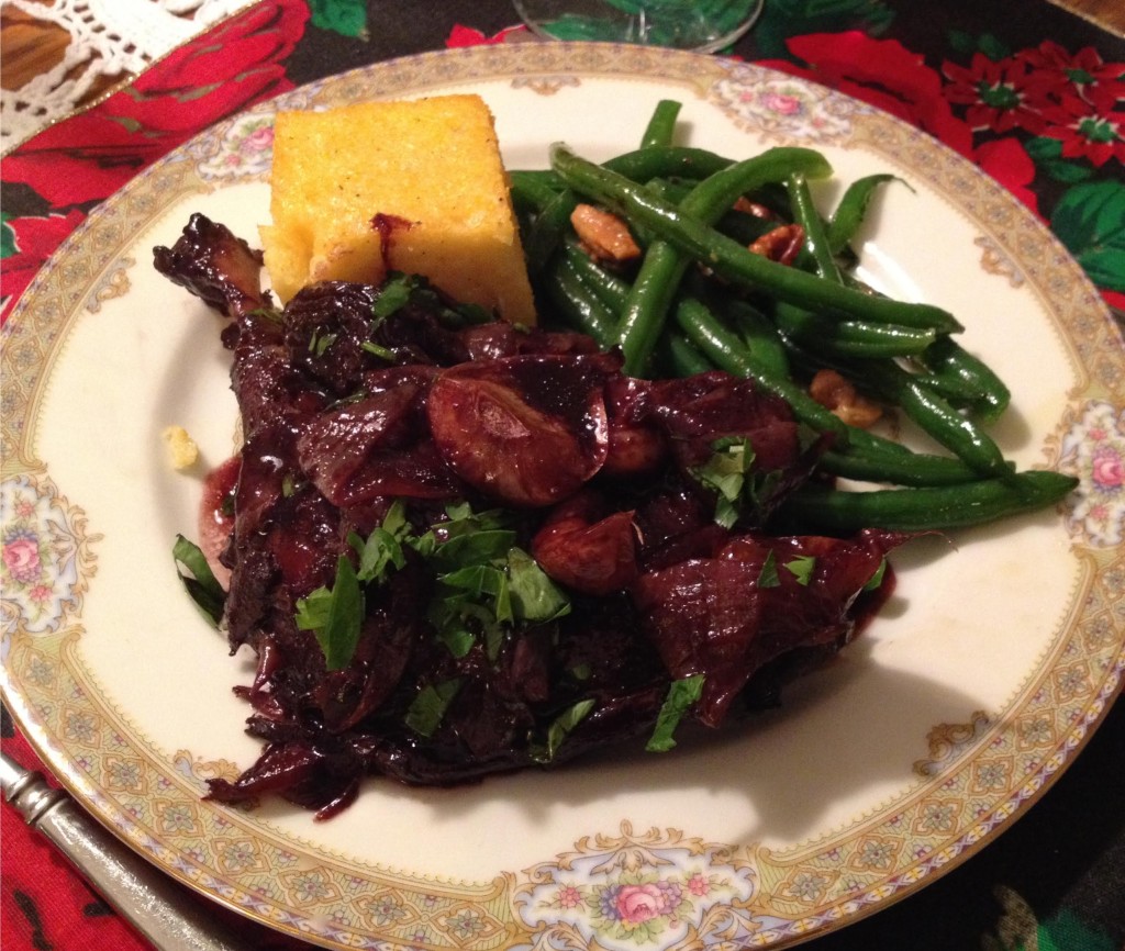 Duck braised with red wine and prunes on a plate.