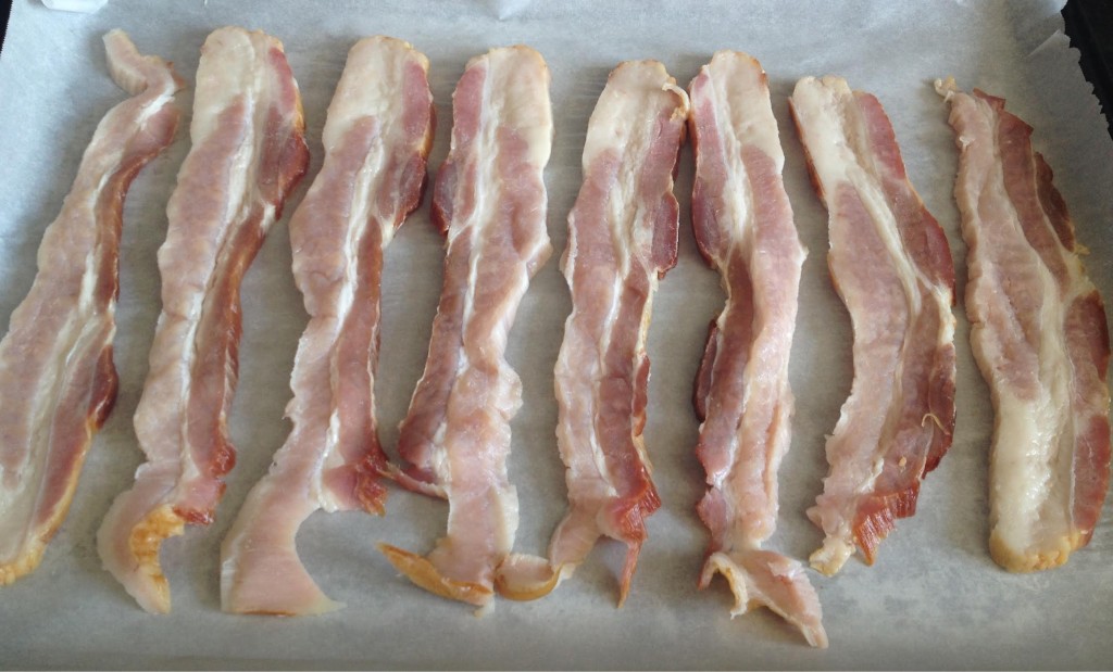 On pound of thick-sliced raw bacon on parchment paper.