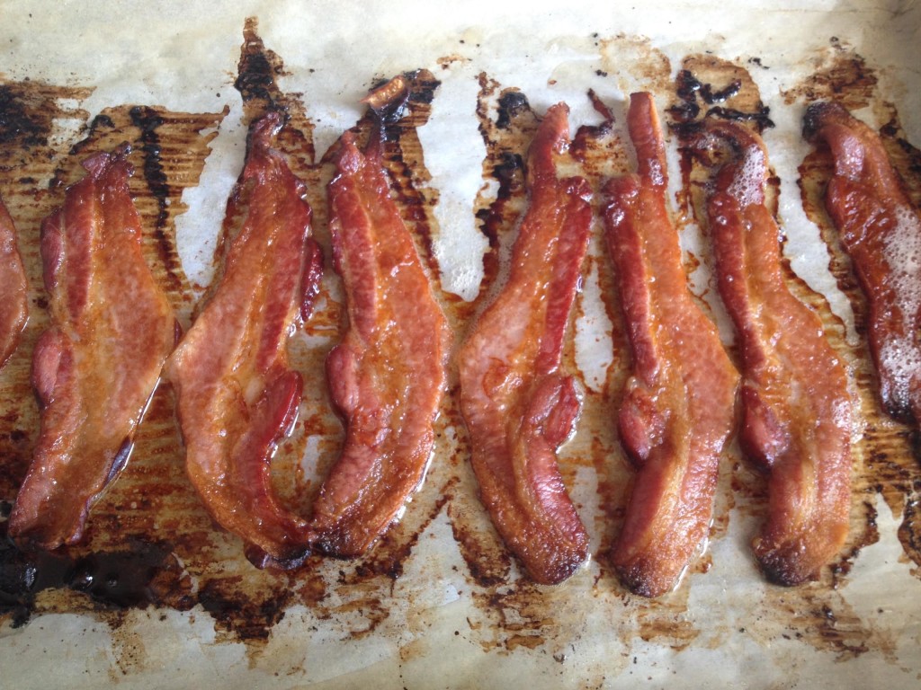 Cooked bacon on a parchment lined sheet.
