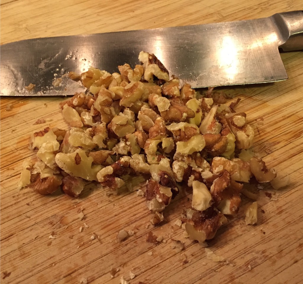 Chopped walnuts on a wooden cutting board.