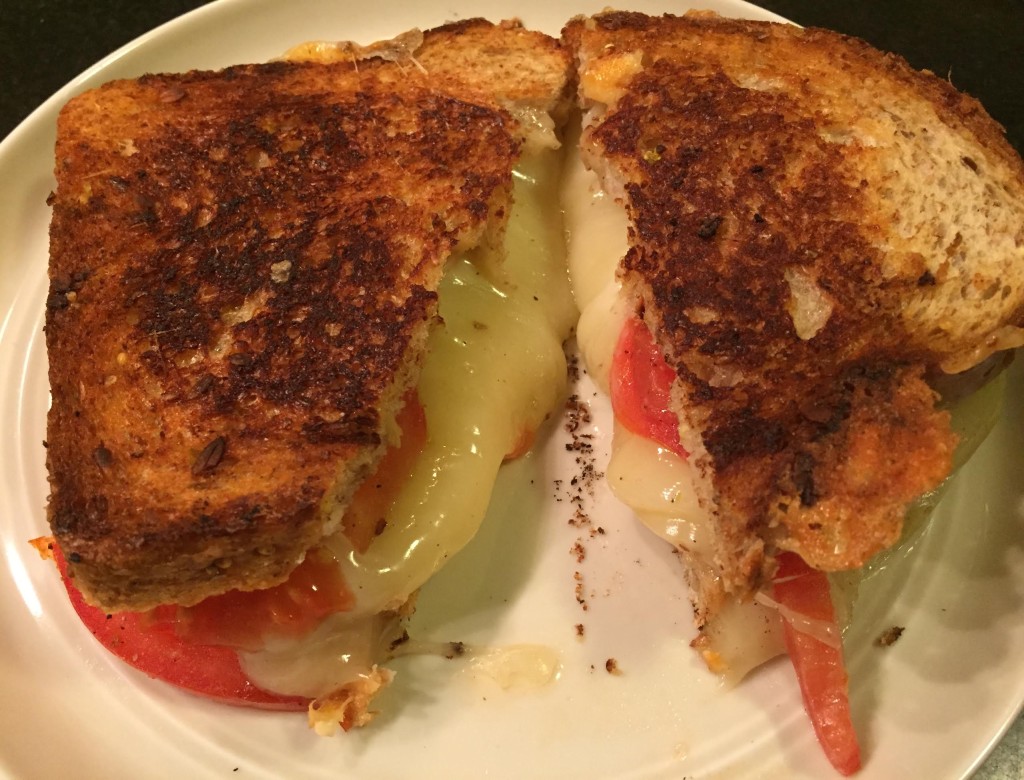 Provolone grilled cheese and tomato sandwich cut in half.
