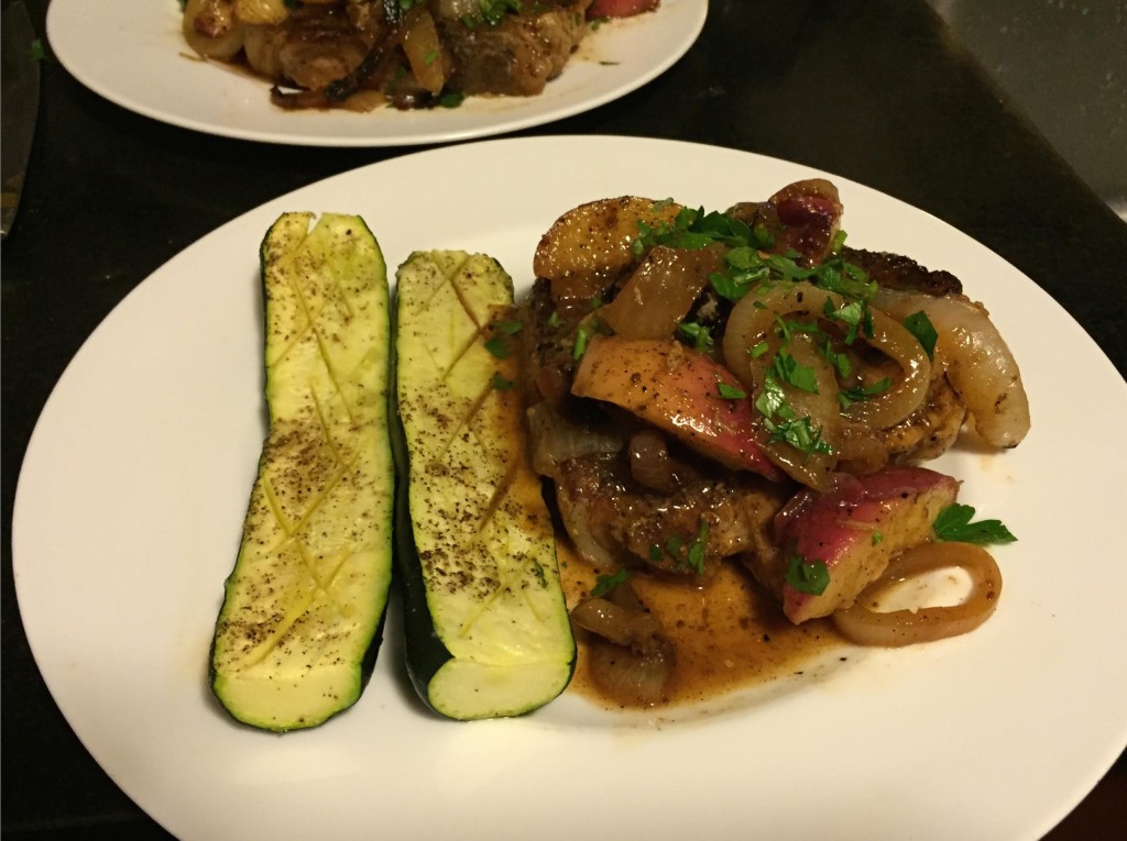 Pork and peaches on a plate with zucchini.