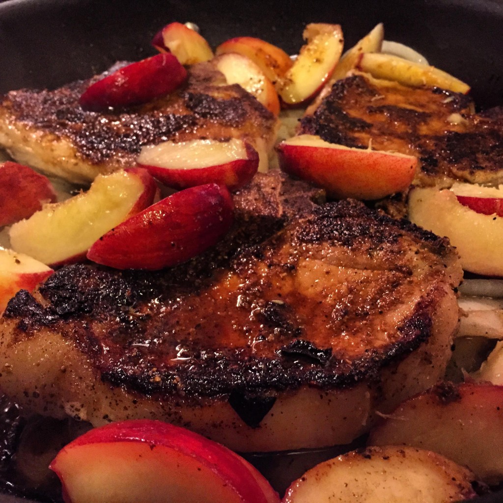 Pork chops with peaches in a skillet.