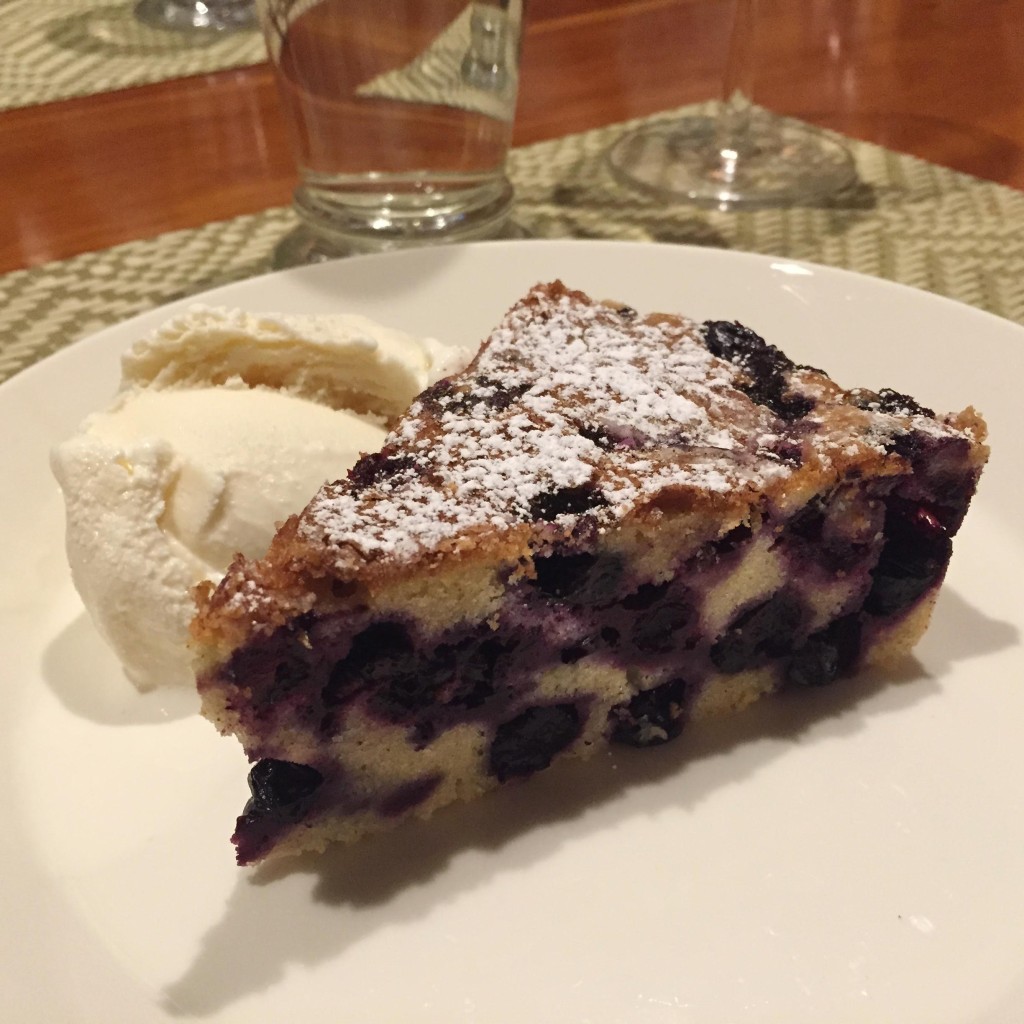 Blueberry buckle piece with ice cream on a white plate.