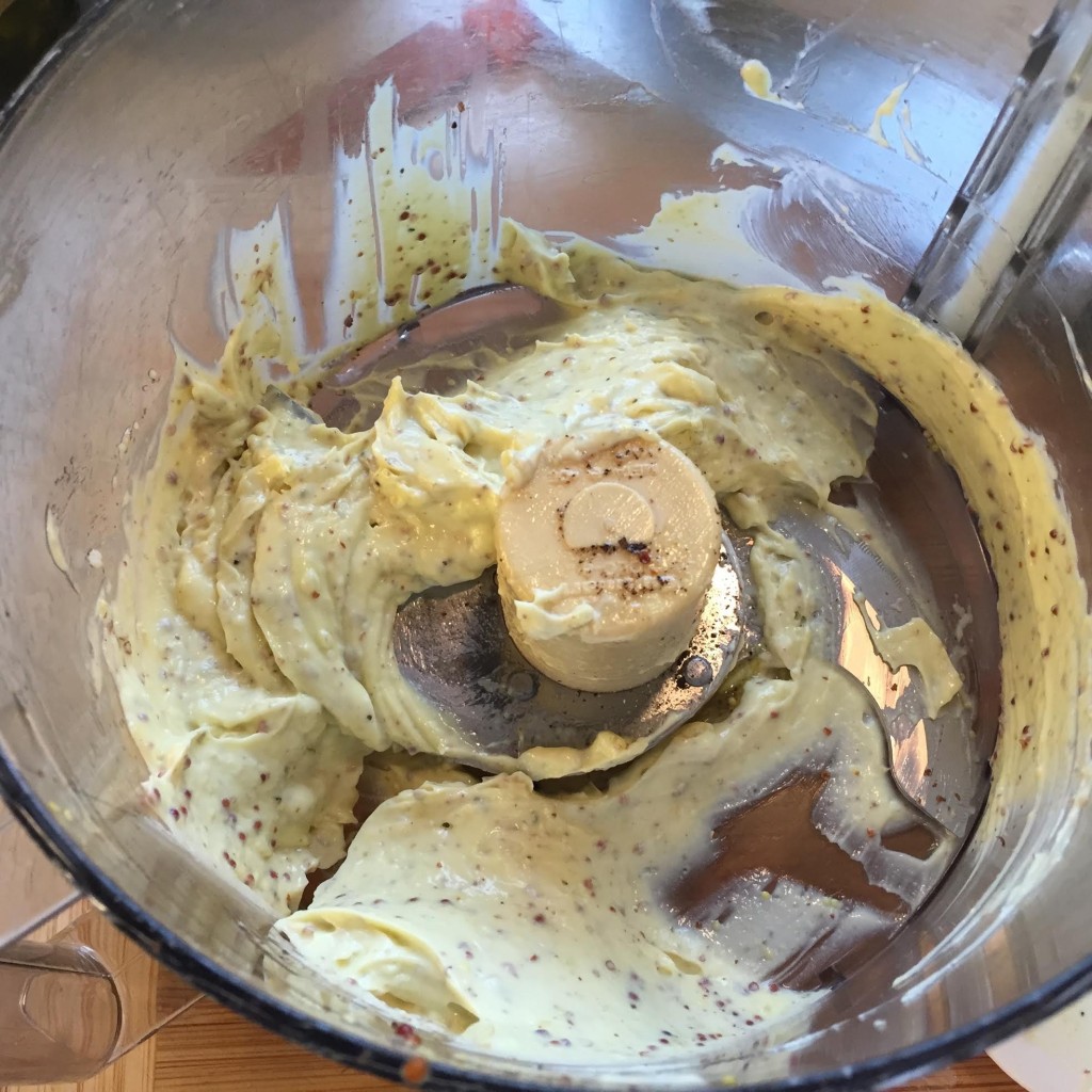 Homemade mayonnaise with grainy mustard in a food processor bowl.