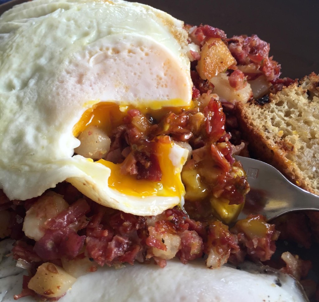 Corned beef hash with and over easy egg breaking the yolk over it.