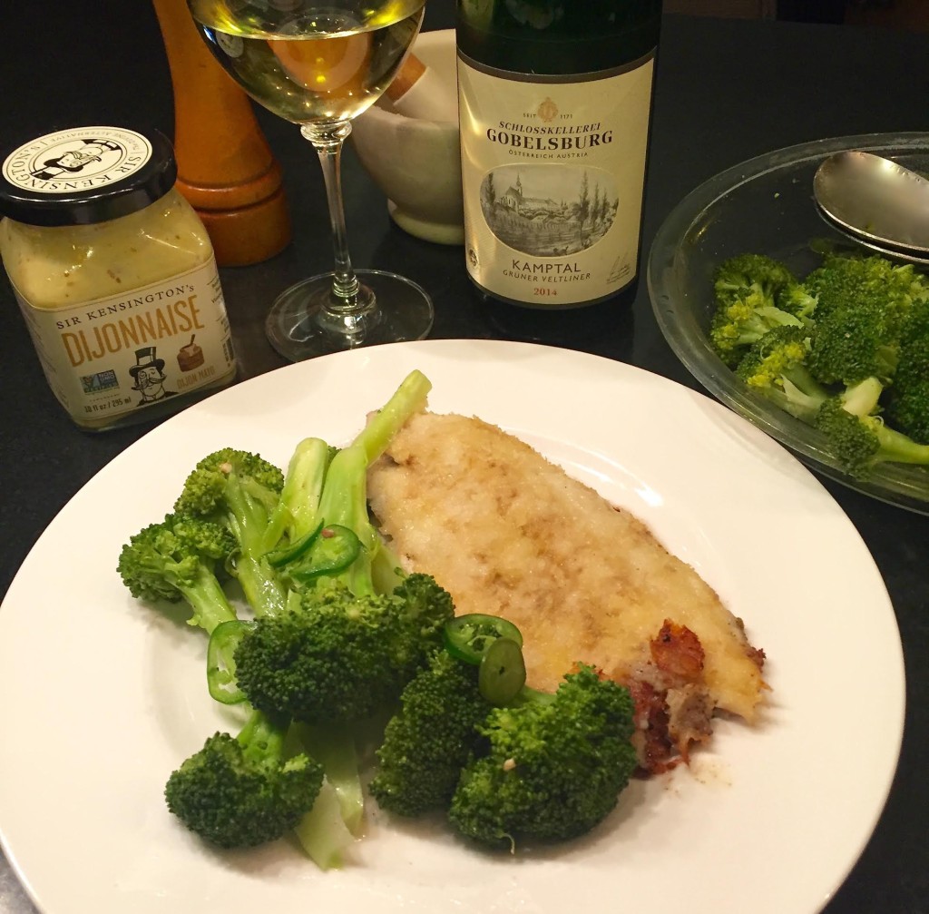 Dijonnaise catfish with steamed broccoli on a white plate.