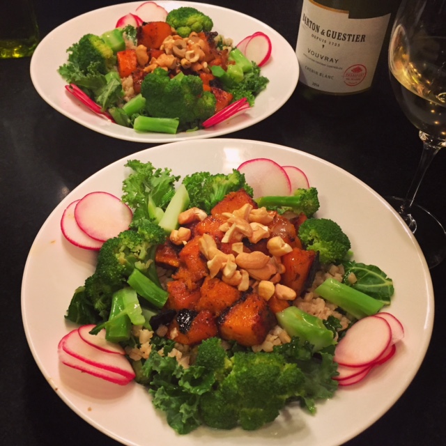 Kale and farro salad with spicy butternut squash, broccoli, radishes and cashews in two white bowls.