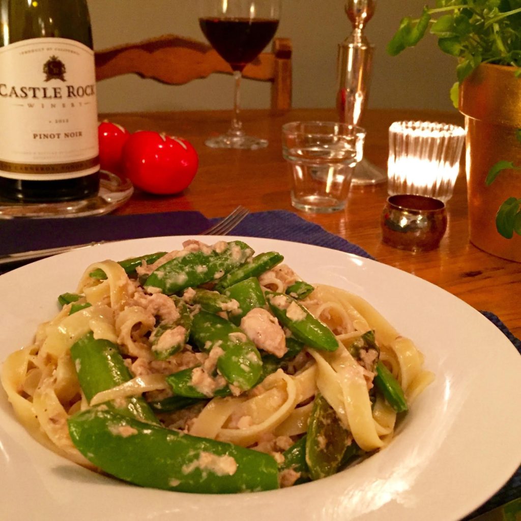Fettuccine with salmon and sugar snap peas in a white rimmed bowl.