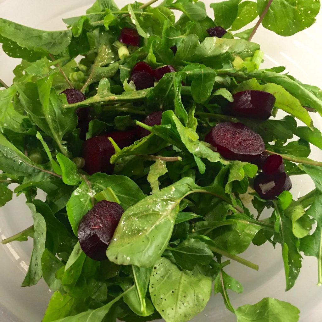 Arugula, roasted beet and scallion salad in a bowl.