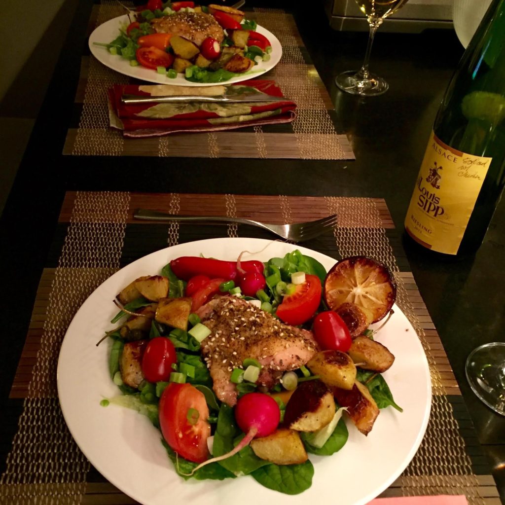 Two dinner salads with chicken thighs and white wine.