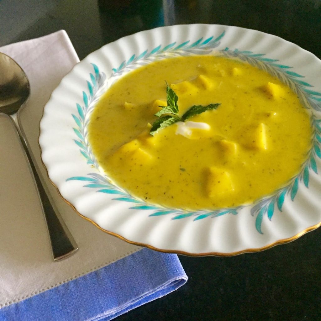 Chilled Curried Zucchini soup with apples, mint and yogurt garnish in a Limoges china bowl.