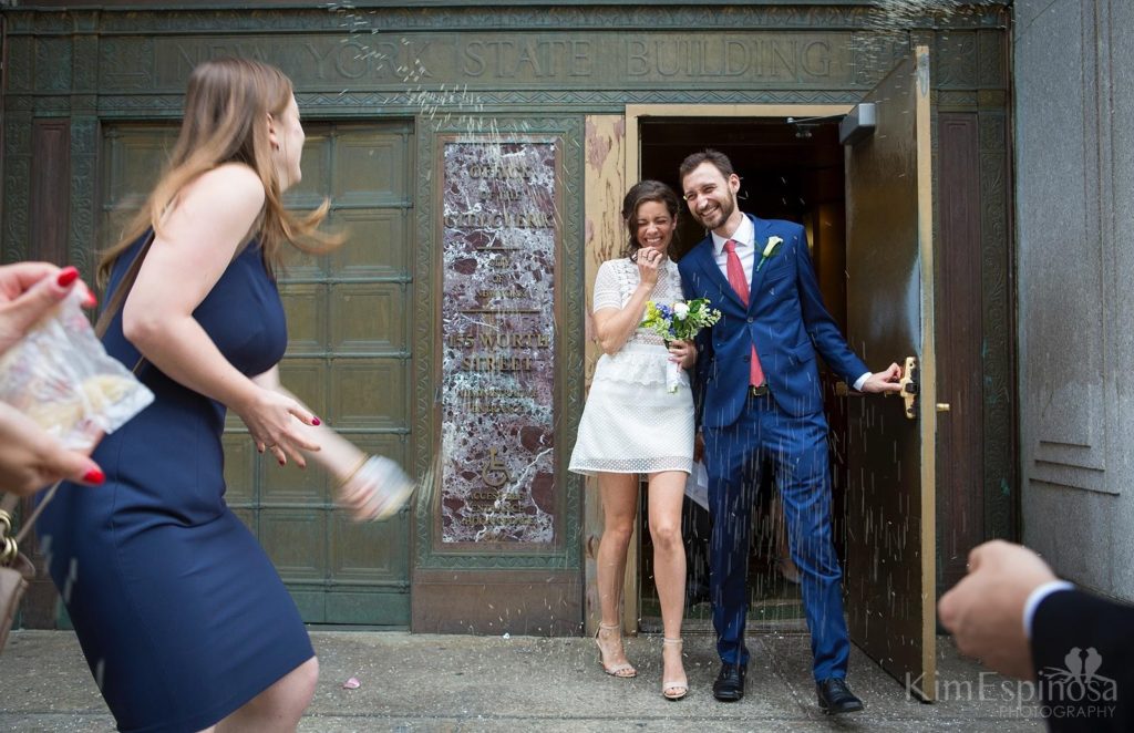 Wedding couple leaving NYC City Hall with rice being thrown.