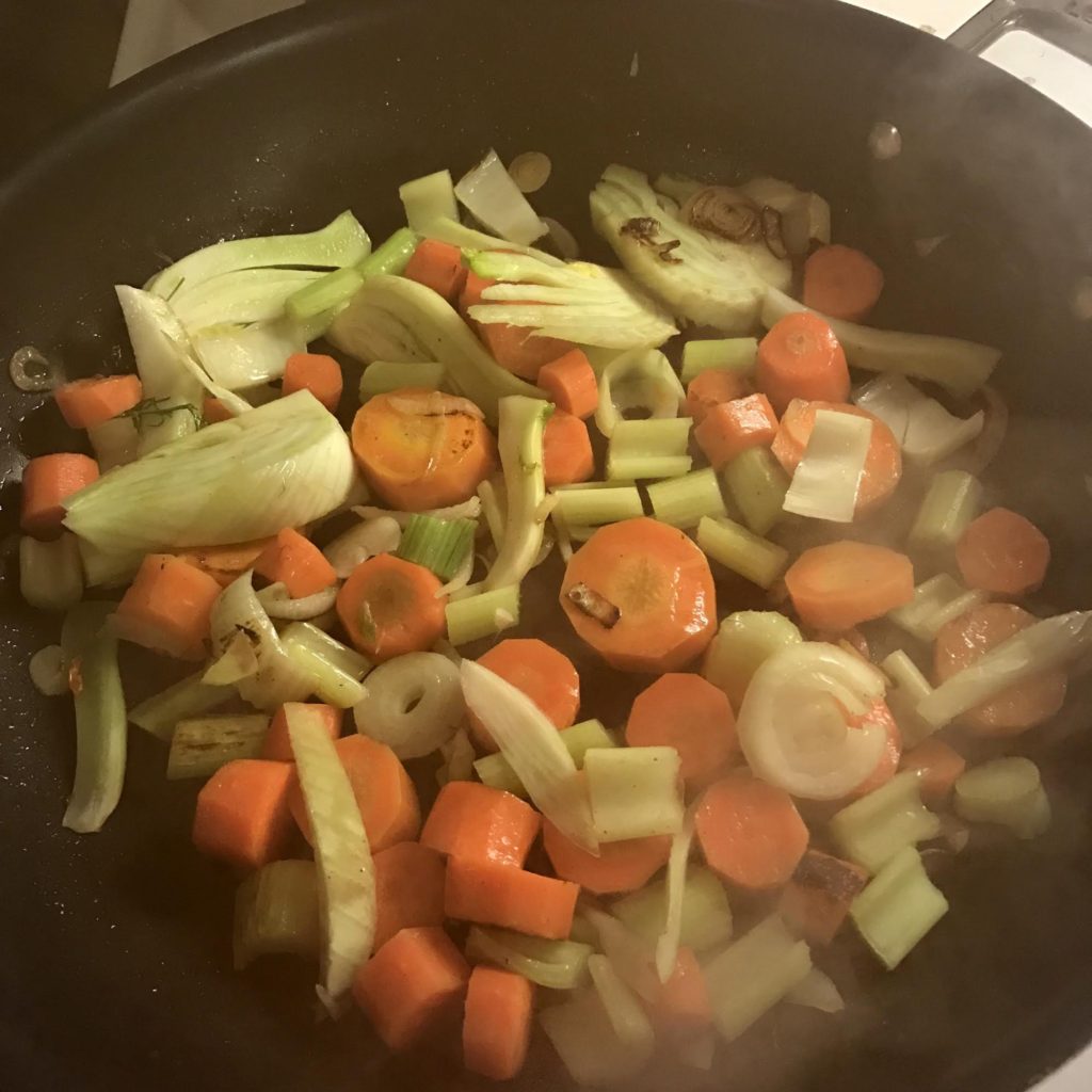 Vegetables sauteeing in a steamy skillet.