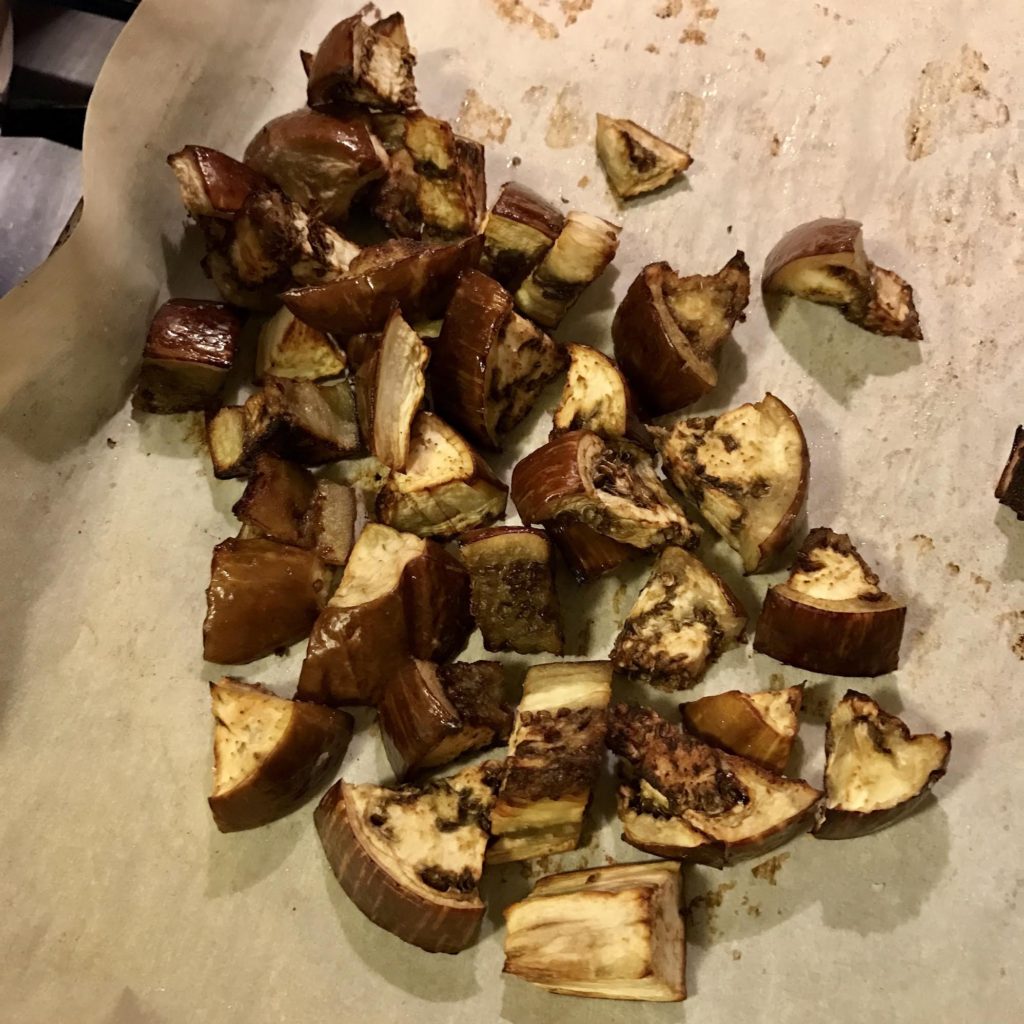 Roasted eggplant on a parchment paper lined baking sheet.