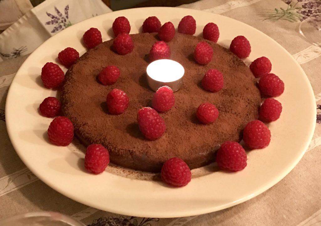 Jean-Georges chocolate cake garnished with fresh raspberries and a tea light.