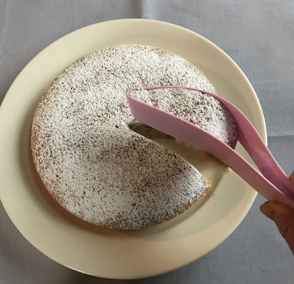 Pecan, olive oil, and Benedictine coffee cake being cut by a pink Magisso cake server.