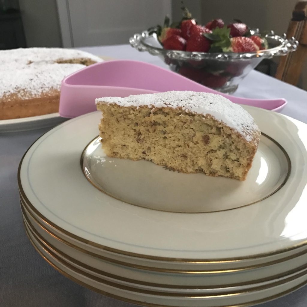 Slice of Pecan, Olive Oil and Benedictine coffee cake with strawberries in the background.