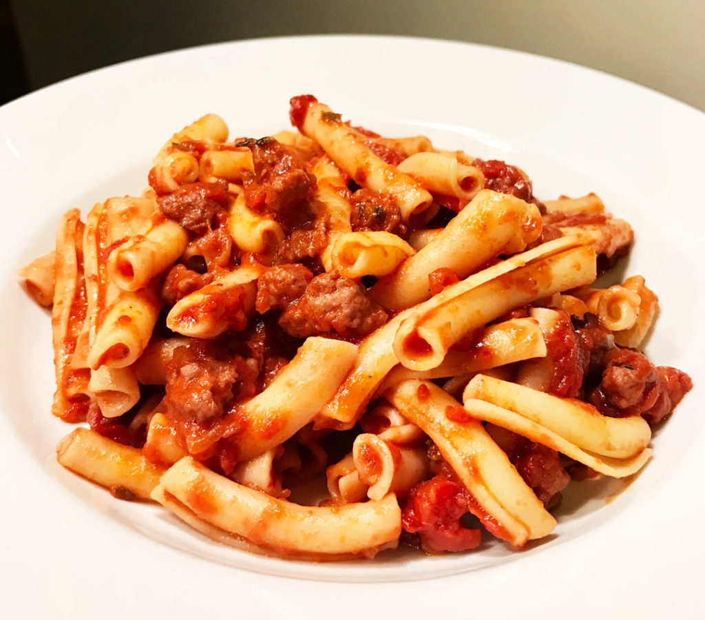 Quick pasta with sweet sausage bolognese in a white bowl - close-up photo.