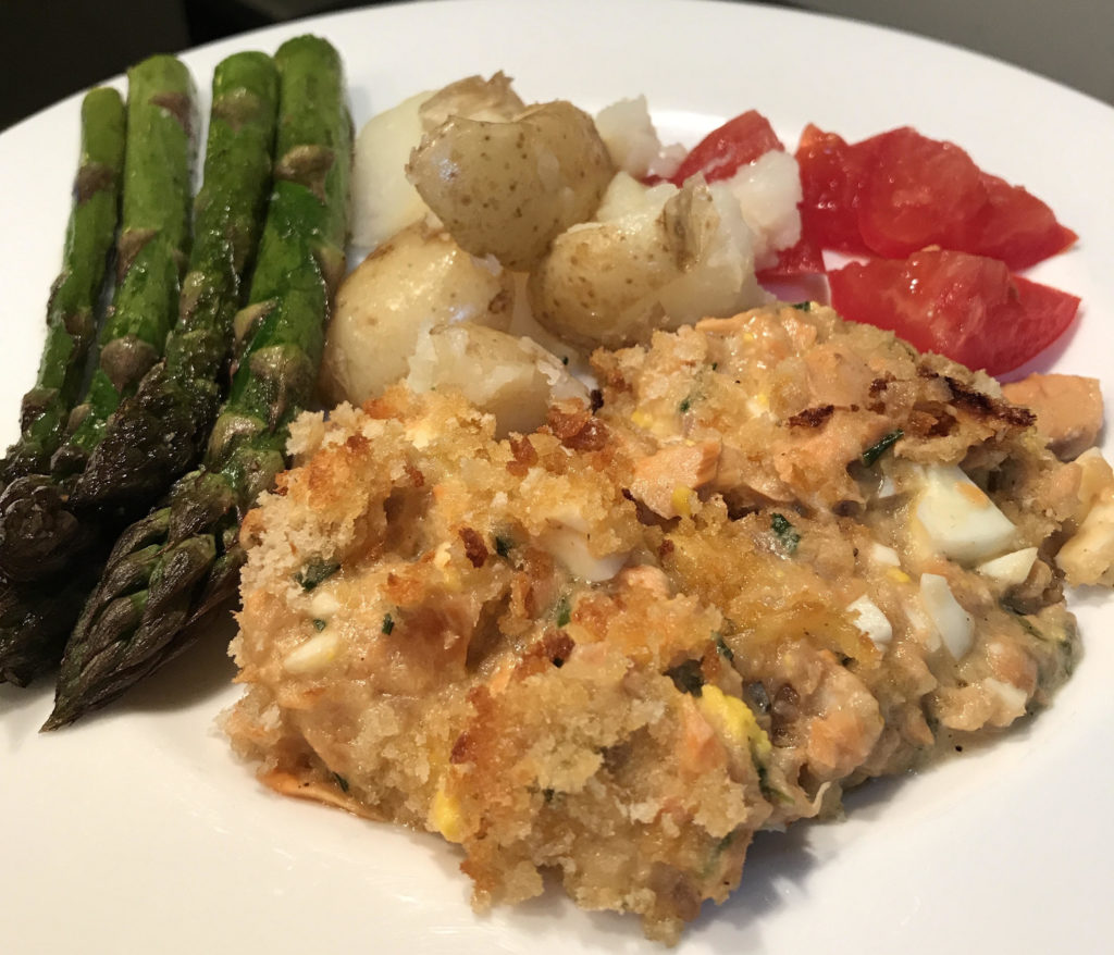 Salmon casserole plated with asparagus, boiled potatoes, and tomatoes.