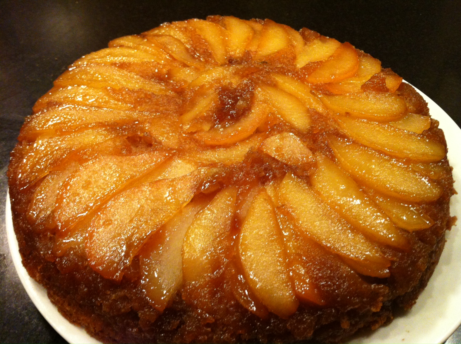 Beautiful pear upside down cake on a white Wedgewood plate.
